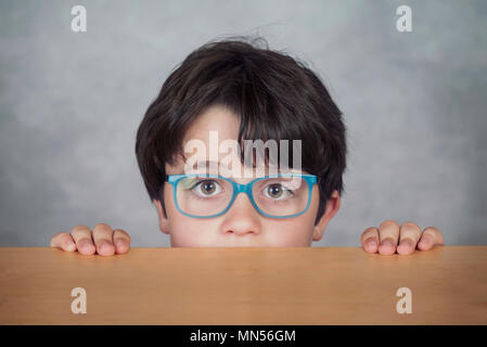 boy with glasses on a wooden table on gray background Stock Photo