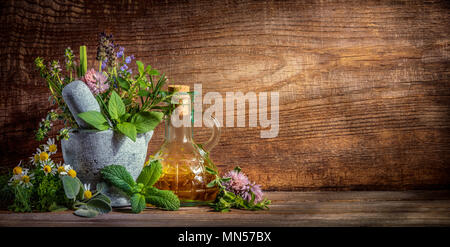 herbs,stone mortar and oil bottle on wooden background Stock Photo