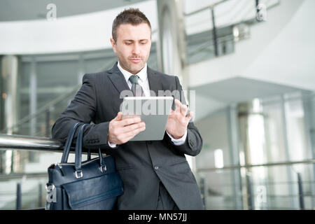 Waist up portrait of successful businessman using digital tablet while waiting for flight in modern airport, copy space Stock Photo