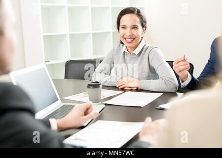 Portrait of cheerful businesswoman in casual wear smiling happily while sitting at table during meeting in conference room Stock Photo