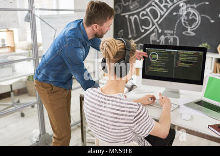 Back view portrait of two contemporary young men in casual wear coding using computer collaborating  on startup project in modern office, copy space Stock Photo
