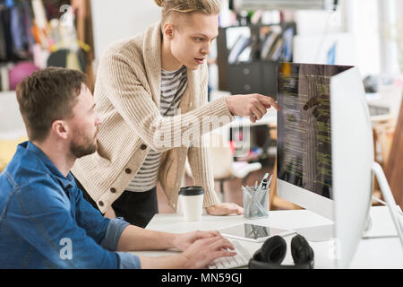 Portrait of two creative young people writing code at desk and  using computer while collaborating with colleague on startup project in modern office Stock Photo
