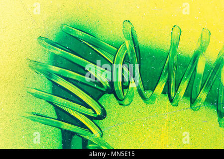 Spiral lines of green paint curves on yellow plastic surface. Abstract birght grunge background Stock Photo