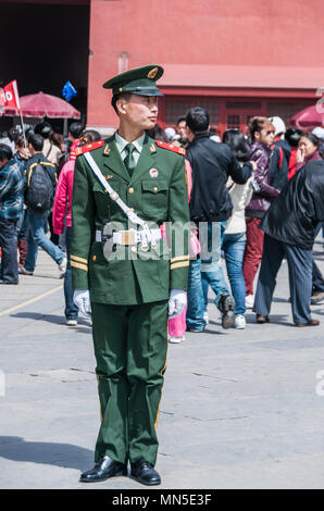 Beijing, China - April 27, 2010: Closeup of Police Officer in green uniform handling mass of people in front of Forbidden city. Many people and red wa Stock Photo