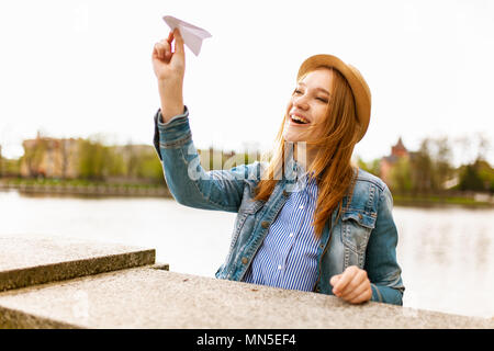 Young beautiful red haired girl throwing a paper plane Stock Photo