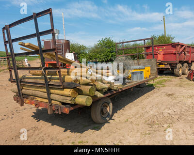 A farm trailer ready for use installing a fence with fence posts tools and rolled wire mesh for stock fencing Stock Photo