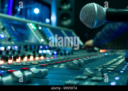 Professional condenser studio microphone over the abstract photo blurred of Hand adjusting audio mixer, Musical instrument Concept Stock Photo