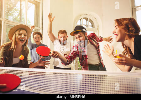 Group of happy young friends playing ping pong table tennis Stock Photo