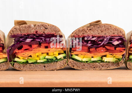 Rainbow salad sandwiches with homemade buckwheat bread, displayed on a wooden board. This fresh healthy lunch is low calorie, dairy free & gluten free. Stock Photo