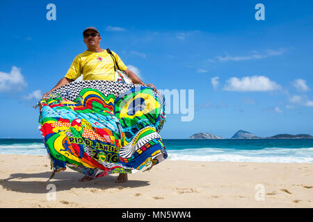 RIO DE JANEIRO - FEBRUARY 10, 2017: A Brazilian vendor selling colorful cangas (sarongs) walks on Ipanema Beach. Stock Photo