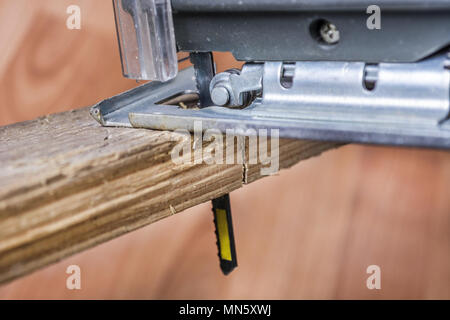 Cutting wood plank with jigsaw electric tool. Saw Blade in plank. Close up, selective focus. Stock Photo