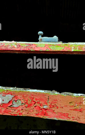 section of a derelict window frame with crumbling peeling red paint and window catch. Stock Photo