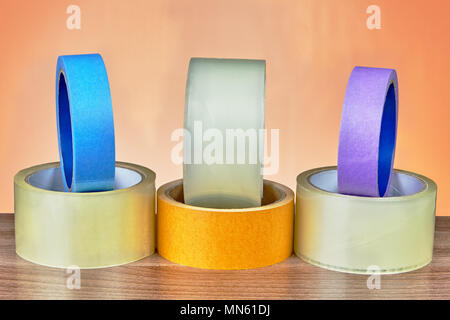 Different types of adhesive tape are lined on an orange background. Stock Photo