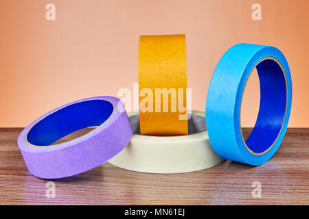 Four colored rolls of  paper and plastic  duct tape lie on the table. Stock Photo