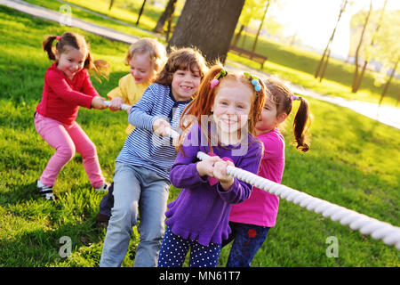 a group of small preschool children play a tug of war in the park.  Stock Photo