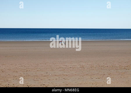 Two people in deckchairs on a Wide open empty beach at Puerto Madryn, Chubut Province, Argentina. Stock Photo