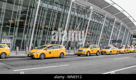 Yellow taxi cabs have formed a line in front of JFK airport's terminal 4. Stock Photo