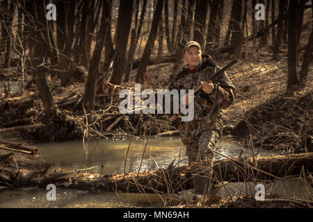 Hunter man forest river with shotgun during hunting season Stock Photo