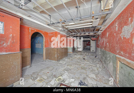 A wide corridor with a collapsed suspended ceiling inside the old abandoned underground Soviet shelter during the Cold War. Stock Photo