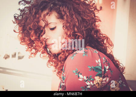 nice red portrait of a red hair girl lost in her thoughts alone at home. warm colors and tones, closed eyes and lonely, beautiful cacuasian young woma Stock Photo