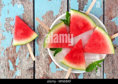 Watermelon slice popsicles on plate with a rustic blue wood background Stock Photo