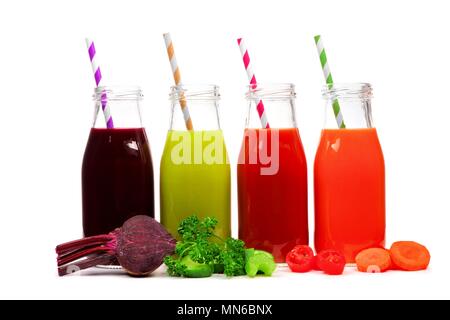 Four bottles of vegetable juice, beet, greens, tomato, and carrot with ingredients, isolated on white Stock Photo