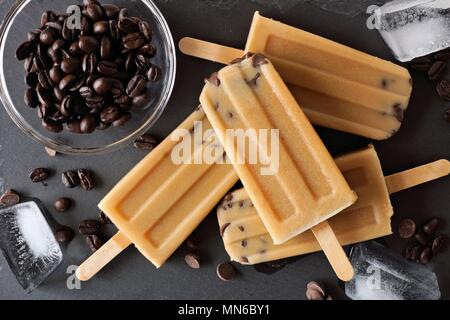 Coffee and chocolate ice pops in a cluster, overhead scene over a slate background