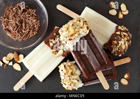 Chocolate and almond ice pops in a cluster, overhead scene over a slate background Stock Photo
