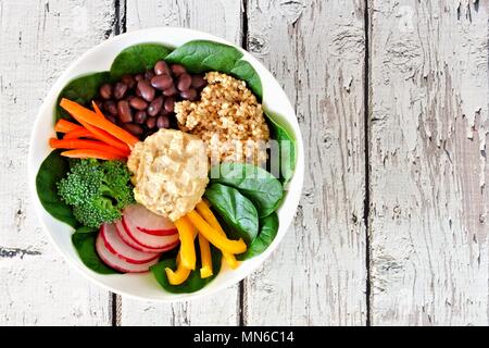 Nourishment lunch bowl with quinoa, hummus and mixed vegetables, above view on rustic white wood Stock Photo