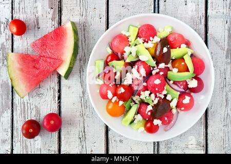 Summer salad with watermelon, avocado, tomatoes and feta cheese, above scene on a rustic white wood background Stock Photo