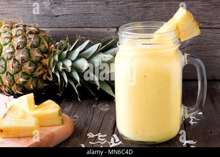 Pineapple smoothie in a mason jar, scene against an old wood background Stock Photo