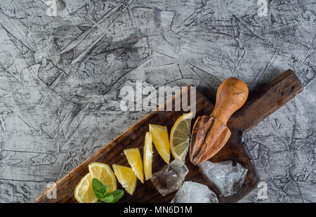 cocktail ingredient: Summer mint and lemon for refreshing cocktail mojito with ice on kitchen board. Stock Photo