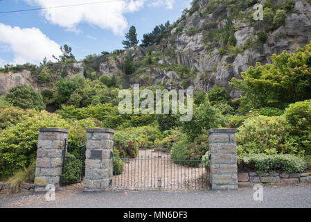 Entrance to the free public Lady Thorn Rhododendron Dell garden with lush greenery and natural rock in Port Chalmers, Dunedin, New Zealand Stock Photo