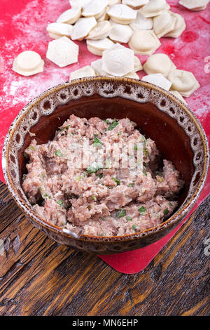 raw homemade dumplings with minced pork on the red surface. Stock Photo