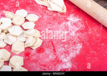 raw homemade dumplings with minced pork on the red surface. Stock Photo