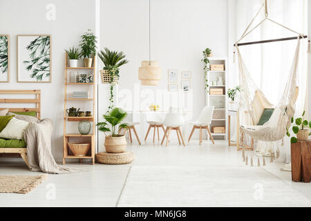 White flat interior with leaves posters and brazilian chair hanging by the window Stock Photo