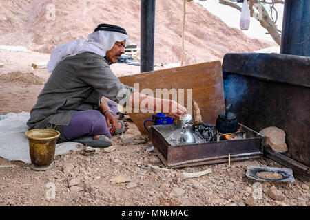 A bedouin sits on the ground and prepare the traditional bedouin coffee on fire Stock Photo