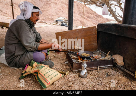 A bedouin sits on the ground and roast coffee beans on fire Stock Photo