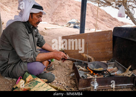 A bedouin sits on the ground and roast coffee beans on fire Stock Photo