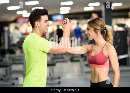 Smiling young man and woman doing high five in gym. Couple wearing sportswear Stock Photo