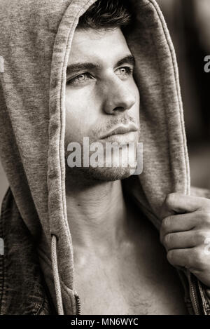 Good looking young man with blue eyes in the street wearing hooded jacket Stock Photo