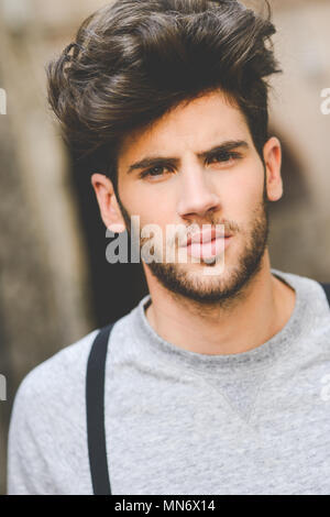 Portrait of young man wearing suspenders and blue jeans in urban background  with modern haircut Stock Photo - Alamy