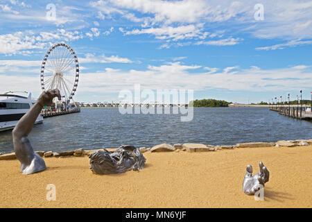 OXON HILL, MARYLAND, USA – SEPTEMBER 11, 2016: Awakening Sculpture of National Harbor on a sandy beach. The giant sculpture with a view on Ferris and  Stock Photo