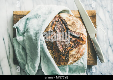 Freshly baked sourdough bread on chopping board Stock Photo