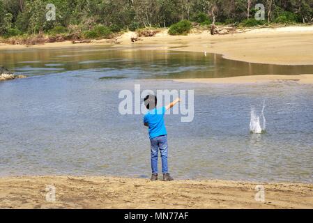 Kid throwing stone in water. Child in action of throwing stone or rock in water. Stock Photo