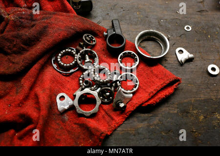 Ball bearings, washers, and other mechanical parts on top of a grease stained table Stock Photo