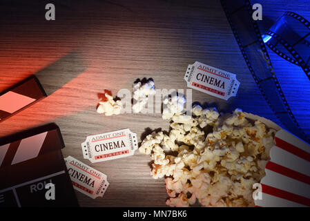 Equipment and elements of cinema on wooden table with colored lights. Concept of watching movies. Horizontal composition. Top view. Stock Photo