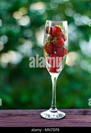 Strawberries in a glass on a green background. Side view. Stock Photo