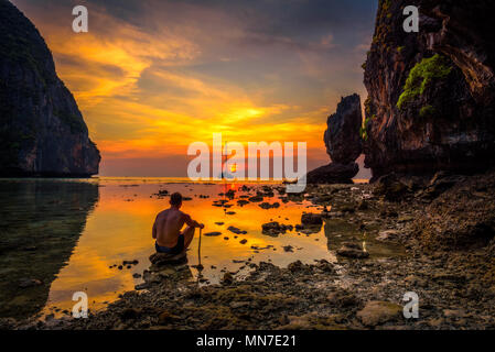 Young boy enjoys dramatic sunset at Maya beach in Thailand Stock Photo