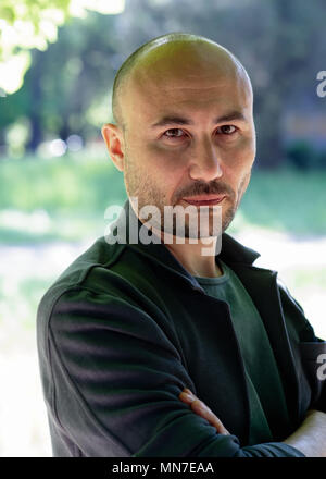 face of a bearded serious bald man in the park. Portrait of a middle-aged man.